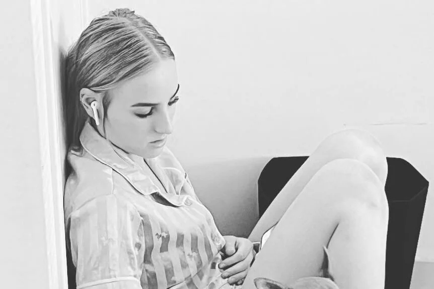 A black and white photo shows Hailee sitting and petting a dog.