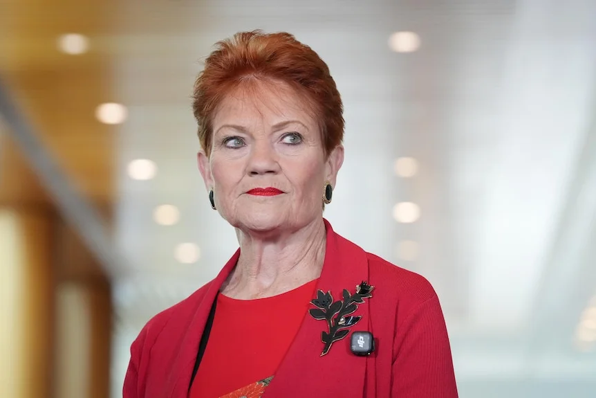 Pauline Hanson wearing red blazer and red lipstick looking pensive. 