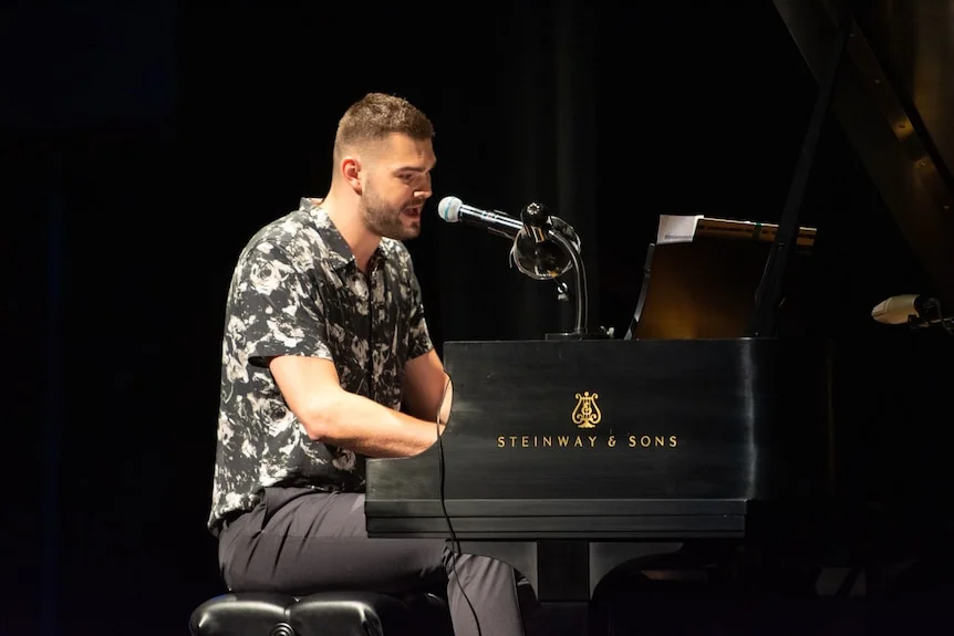 A man playing the piano and singing onstage