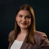 A headshot of a smiling woman with a dark background