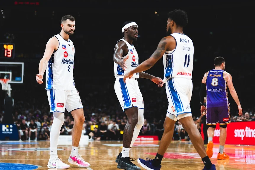 Three Adelaide 36ers players encourage each other during a match