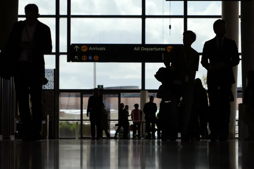 A dark silhouette of passengers inside an airport terminal.
