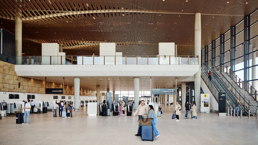 A mockup photo of passengers smiling with luggage inside Western Sydney Airport terminal.