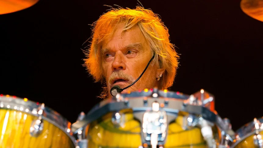 A man sits behind a drum set.