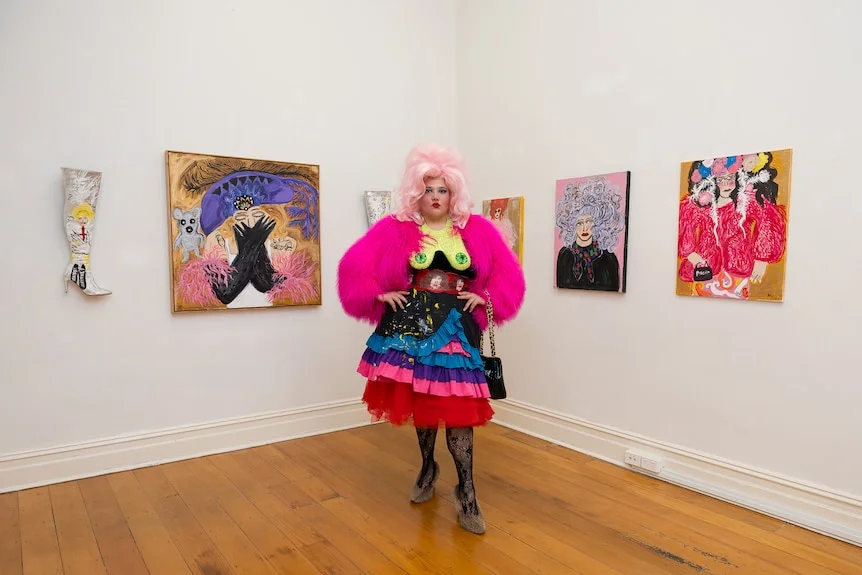 A woman in an art gallery wearing a bright, flamboyant outfit.