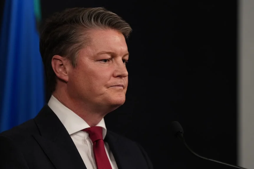 A man in a suit and tie, looking serious.