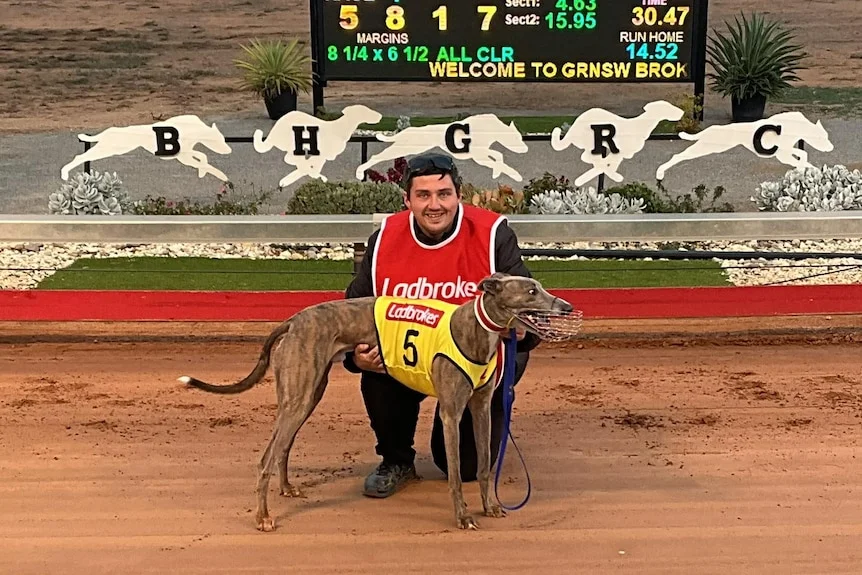 A greyhound trainer with a dog at Broken Hill Racecourse