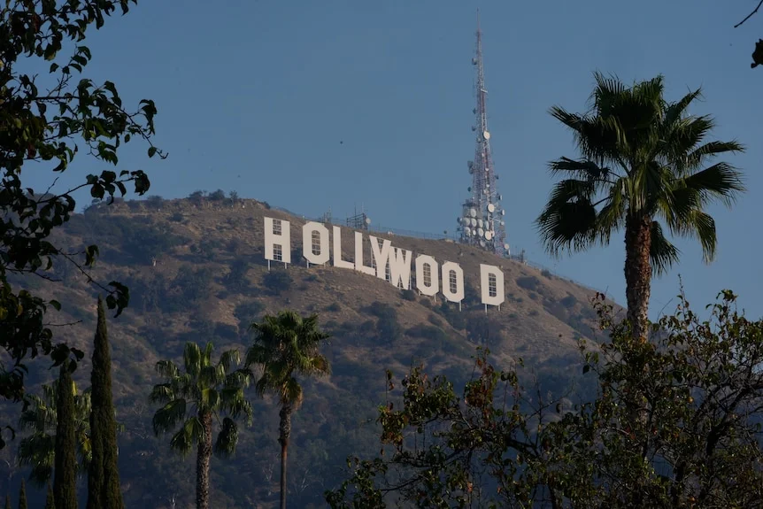 The white Hollywood sign seen through the tops of palm trees
