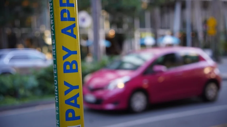 A sticker on a street pole advertises a parking app