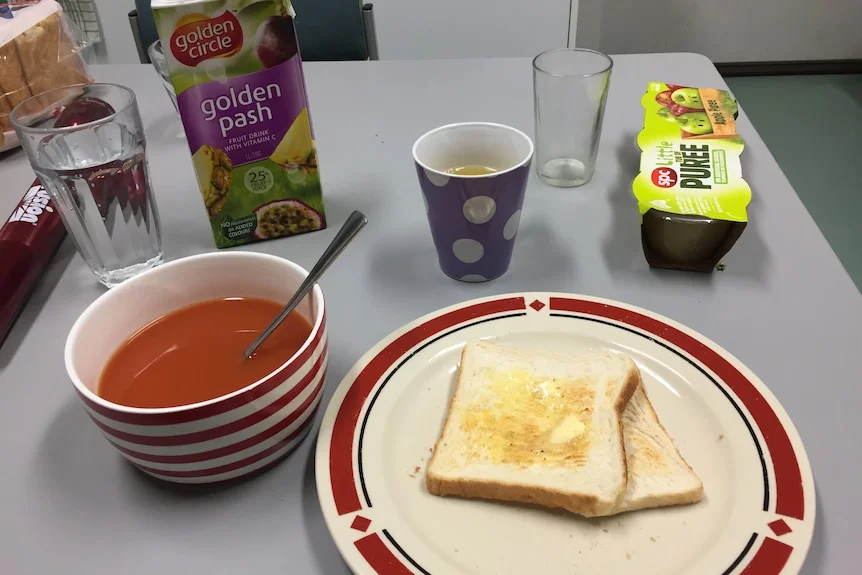 A plate with buttered white toast next to a bowl of tomato soup.