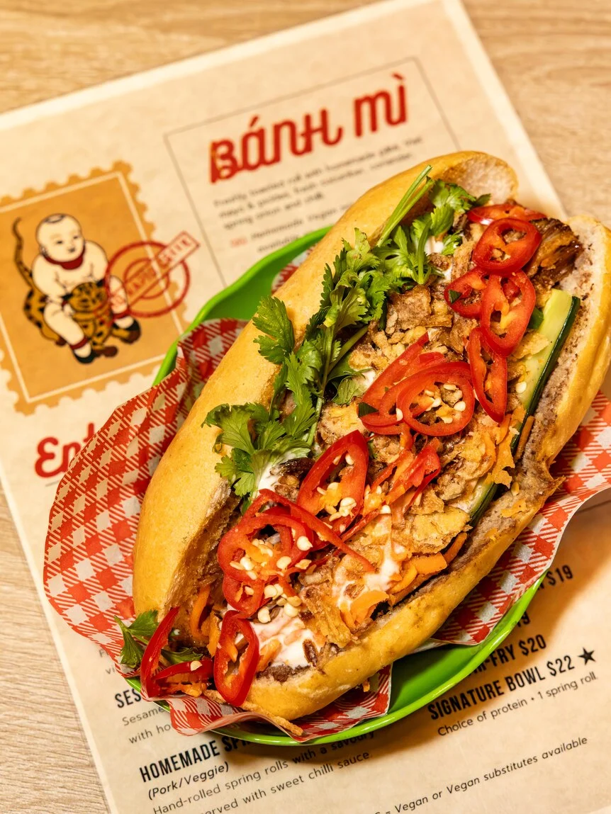 An open banh mi sandwich, which is topped with chilli slices and coriander.