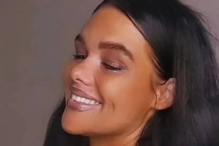 Woman with makeup opens her eyes slightly while smiling