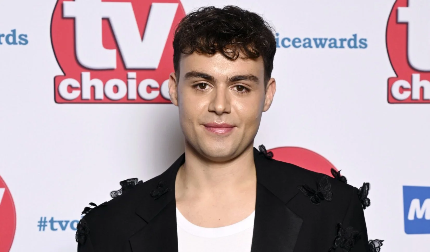 Bradley Riches in a black suit jacket and white t-shirt posing at the TV Choice Awards.