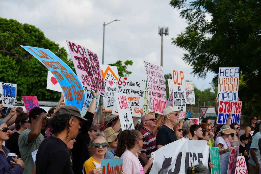 A group of about two dozen protesters holding signs outdoors.