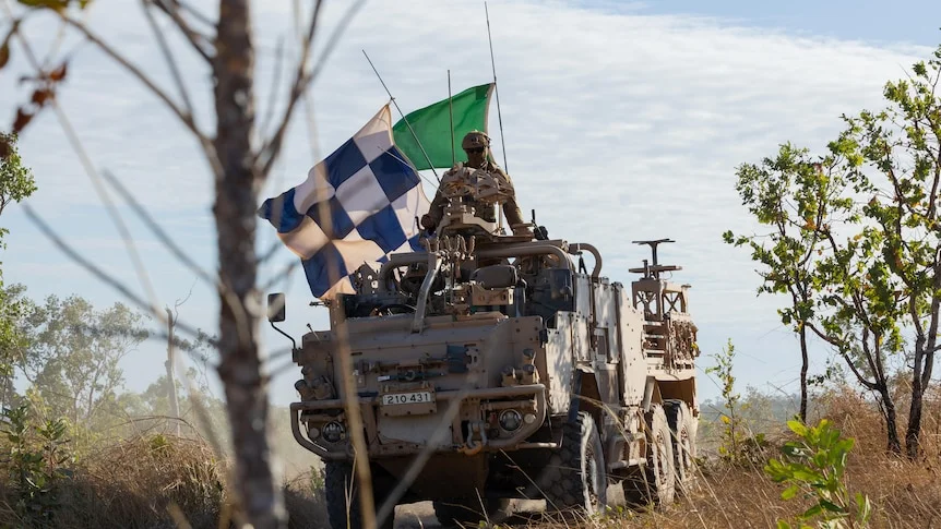 A Supacat military vehicle with large flags.