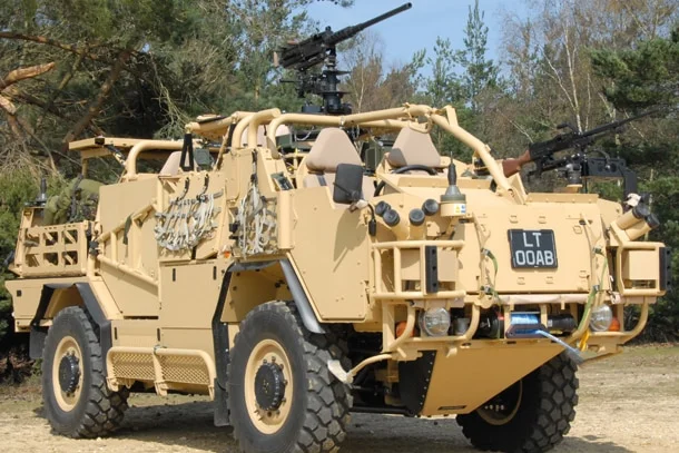 a beige coloured four wheeled military truck with long range weapons fixed to the top