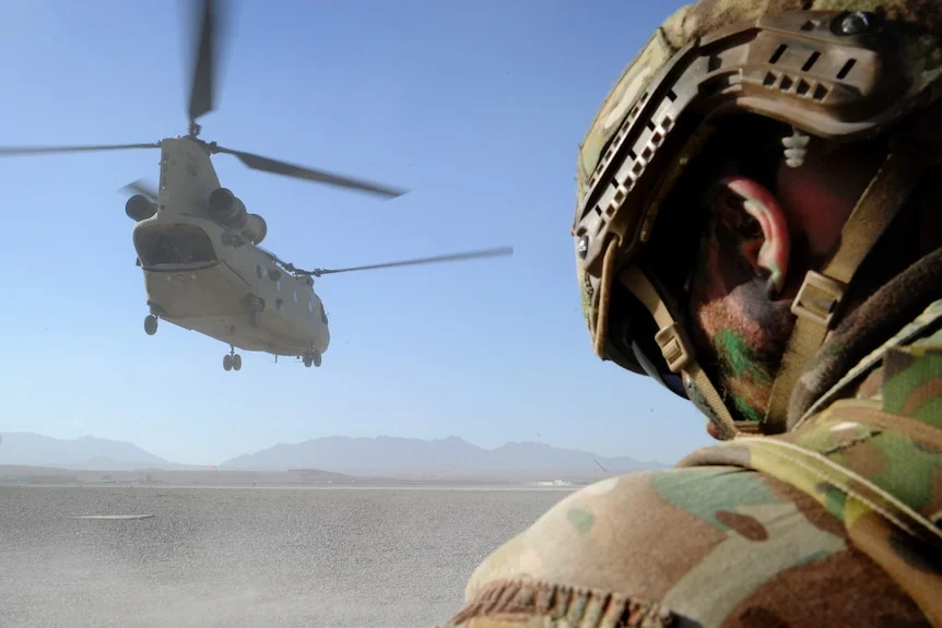 A soldier is seen from behind as a helicopter takes off in Afghanistan.