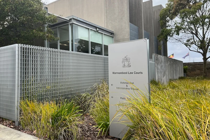 A sign for Warrnambool Law Courts outside a modern building and metal fence