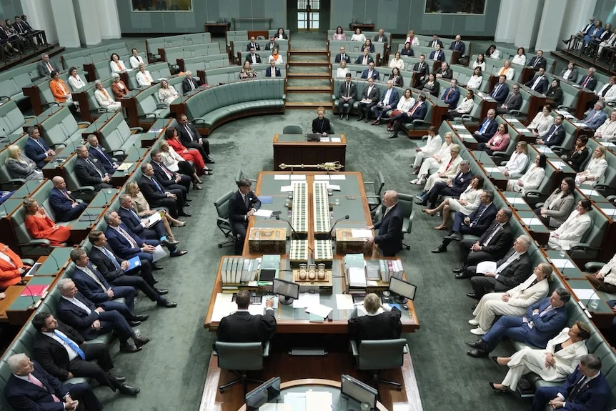 MPs, many wearing white or orange, sit in the House of Representatives.