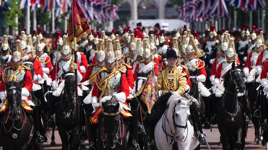 A British military parade with cavalry on horseback. Flanked by rows of union jack flags.