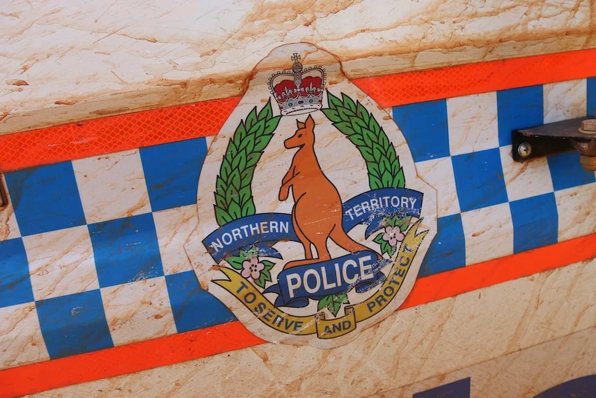 NT Police insignia on mud-splattered car door.