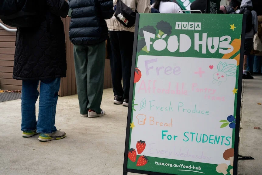 Students lining up with a sign that says "FOOD HUB"