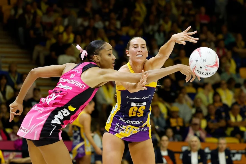 A Thunderbirds player and Lightning player reach across each other for the ball