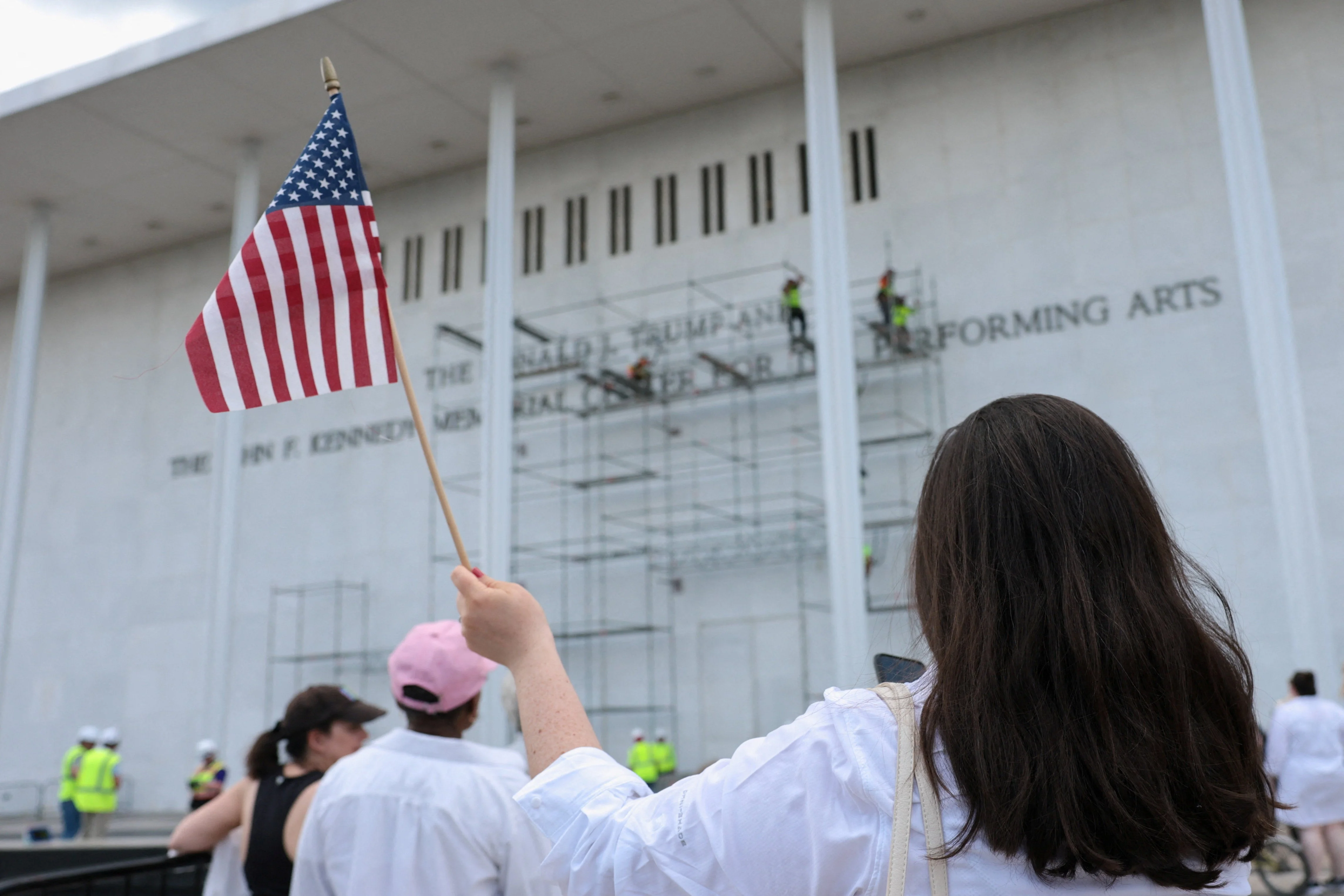 A crowd gathered outside the venue cheering on construction workers and chanting ‘take it off’ before the crew left the site during an afternoon downpour