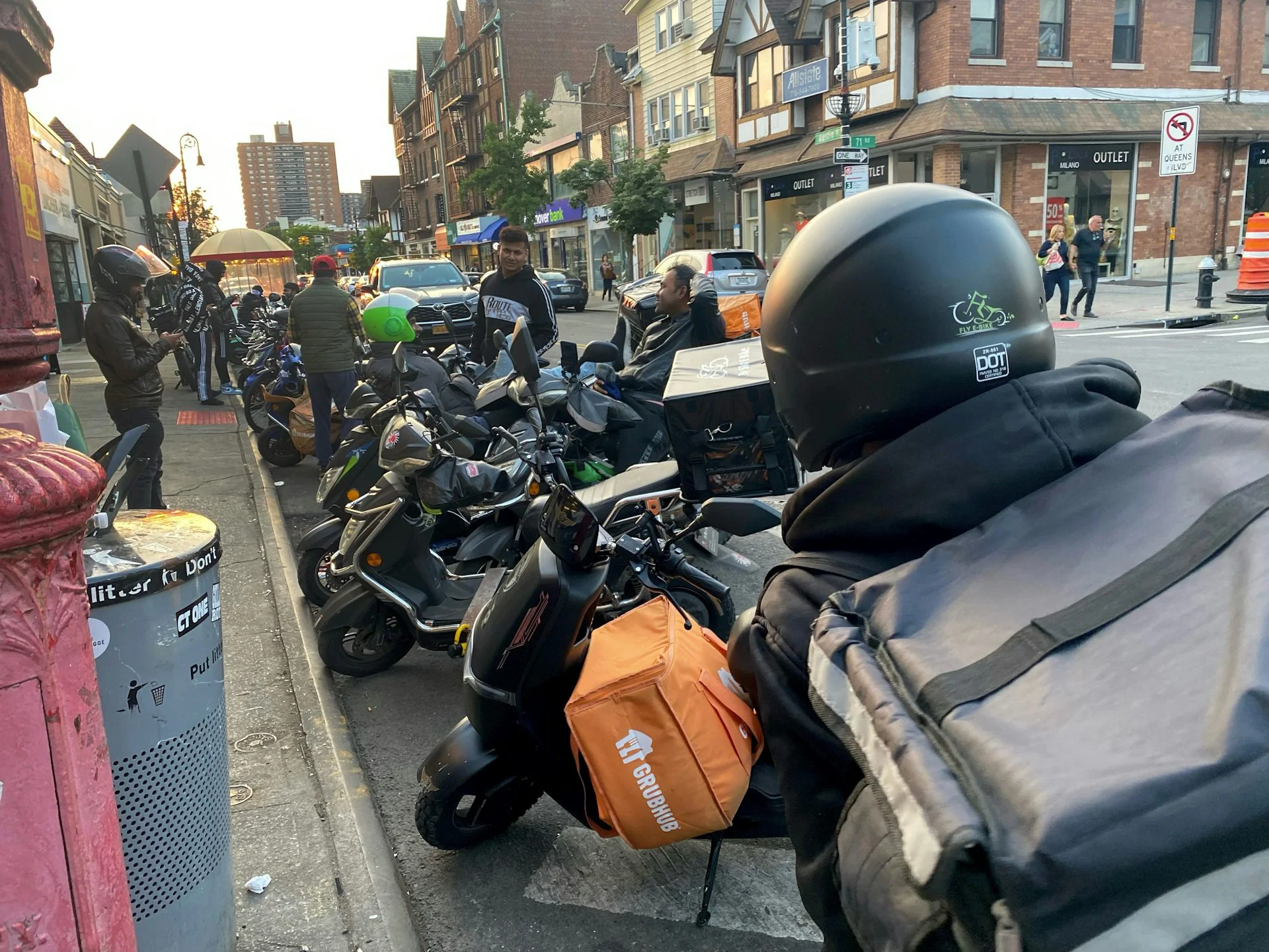 A big group of delivery workers people seen on a street with their motorcycles.
