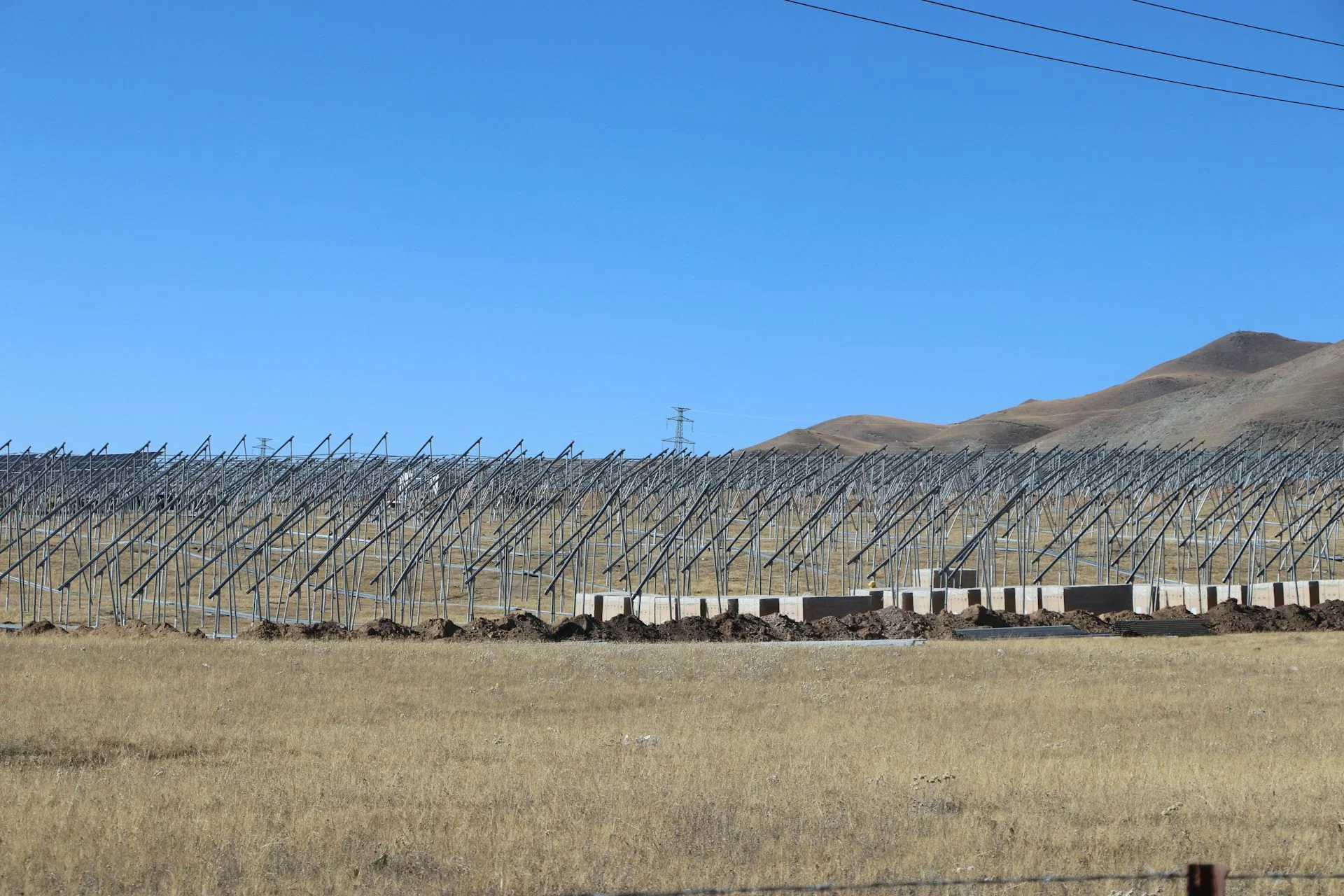 Rows of metal frames stand on flat land.