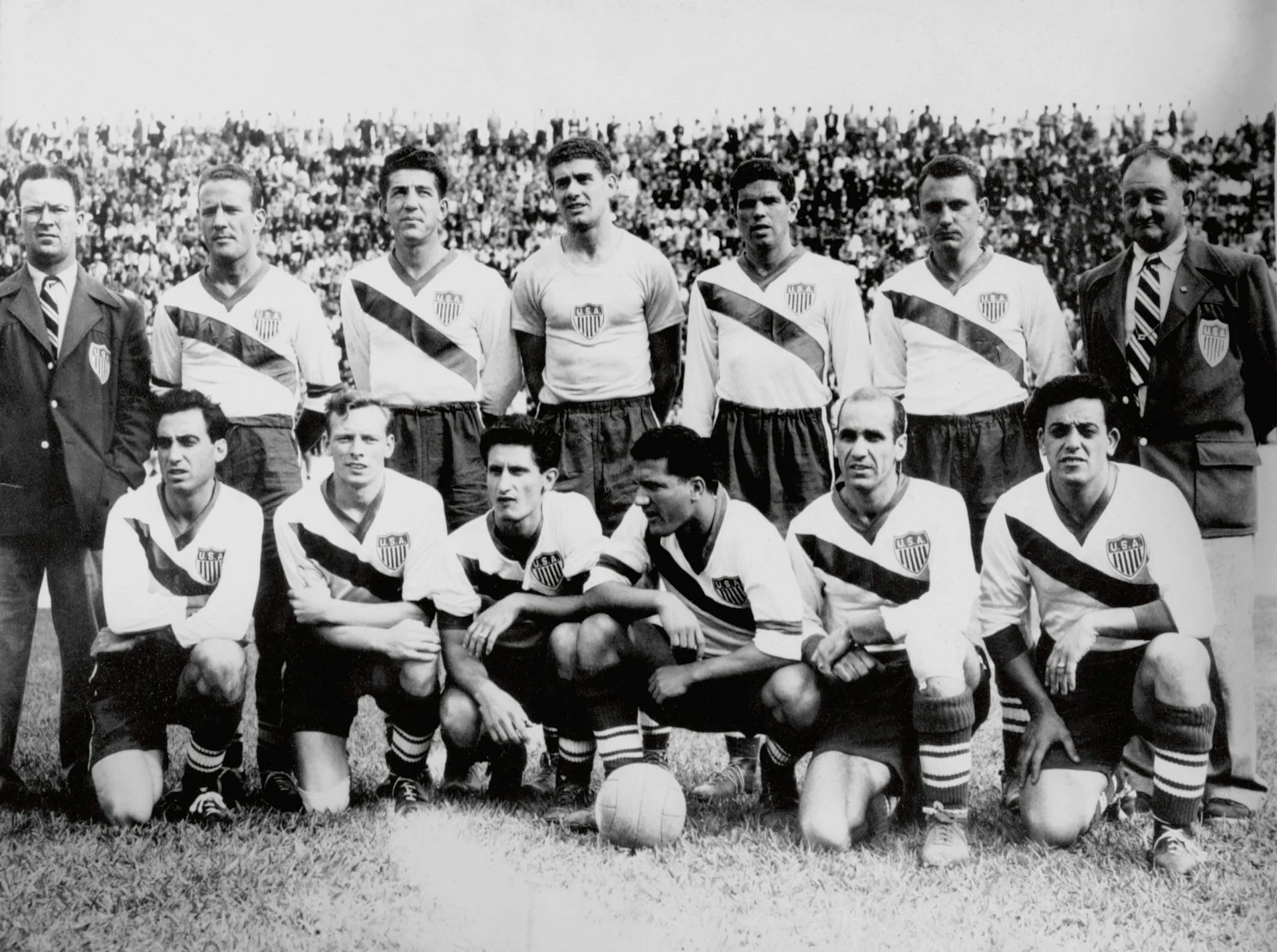 A black and white photo shows a group of men in soccer jerseys.