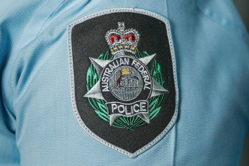 An Australian Federal Police shoulder Insignia on a Blue Uniform shirt.