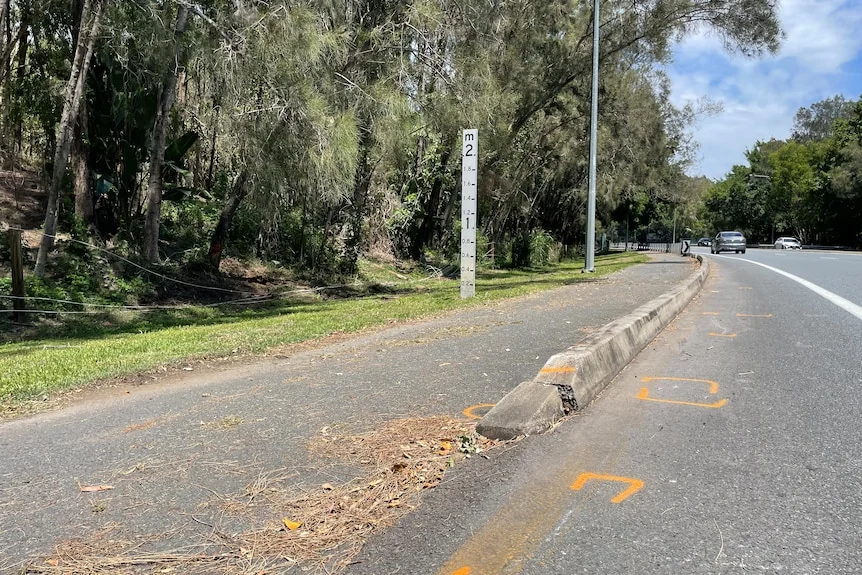 A road and footpath with a flood marker.