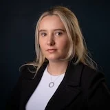 A woman with blonde hair wearing a black blazer and white top