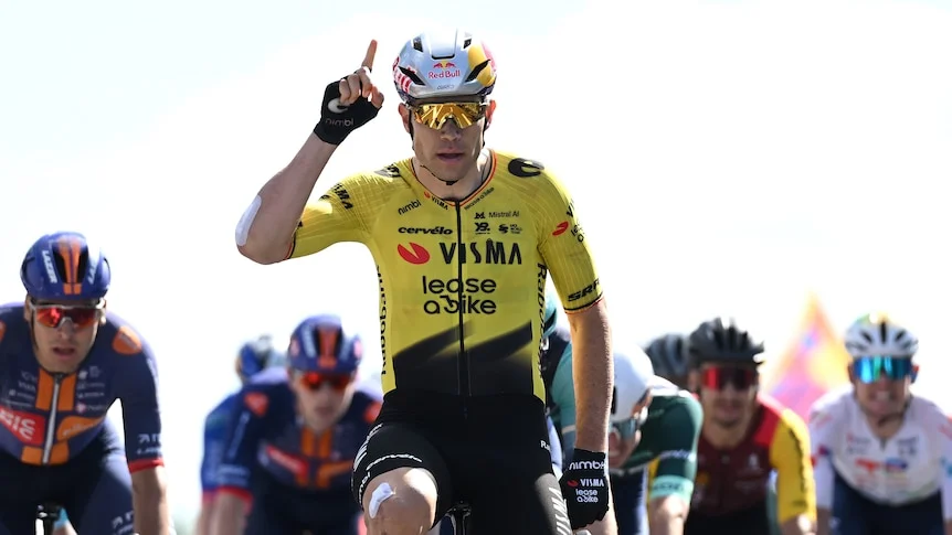 A man points his finger to the sky while riding a bike.