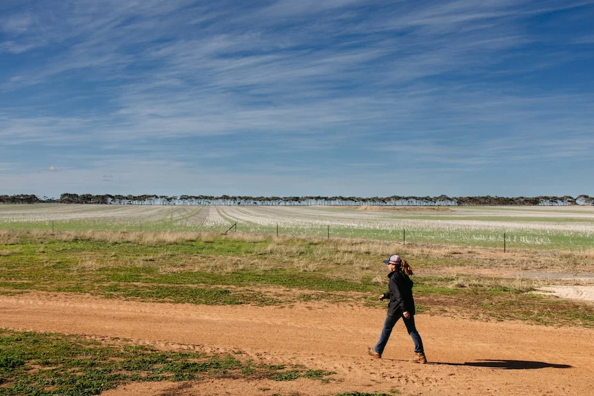 A young woman walking along a dirt road at a farm in WA.