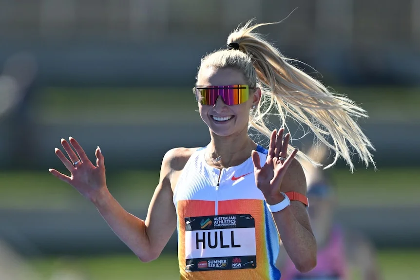 Jess Hull smiles and waves after winning a race. 