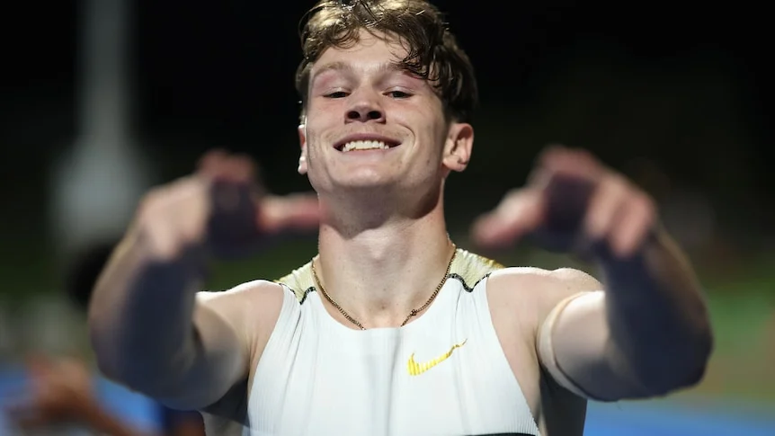 Sprinter Lachlan Kennedy smiles and points at the camera with two outstretched hands