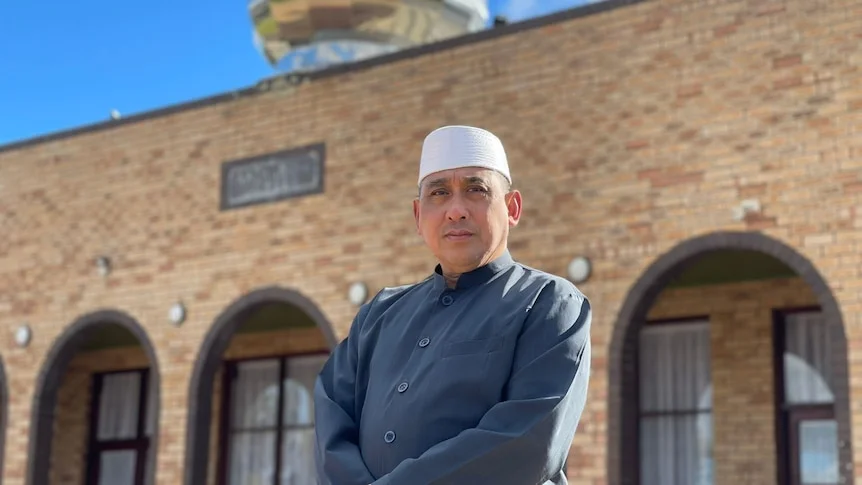 Katanning Imam Alep Mydie stands in front of a brick building 