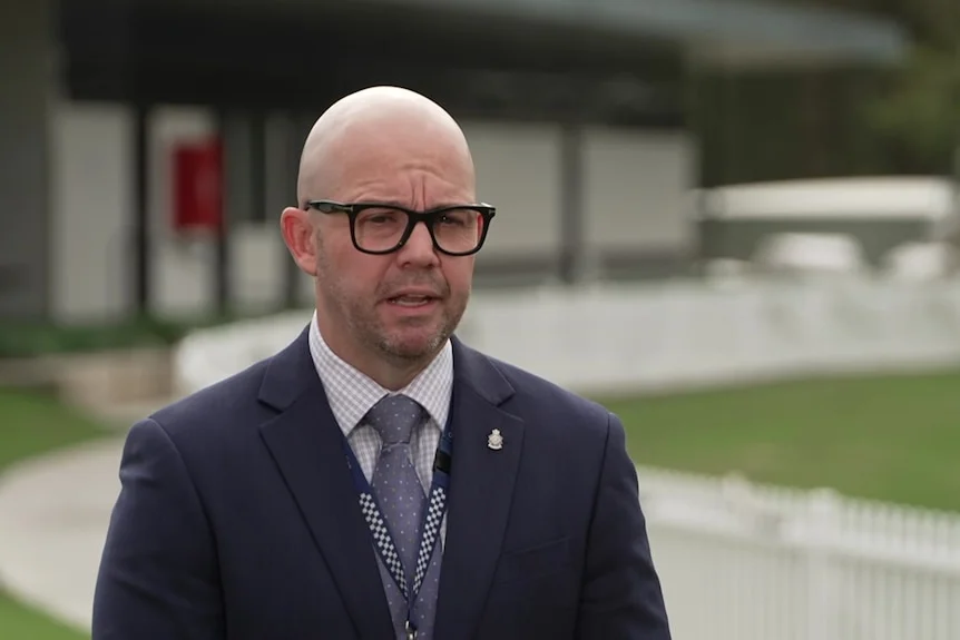 Shane Prior, a bald man with glasses, speaking. 