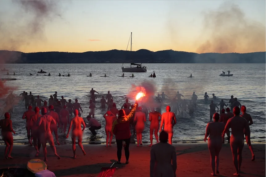 Crowd of swimmers prepare to enter the water for Dark Mofo's 2026 Nude Solstice Swim