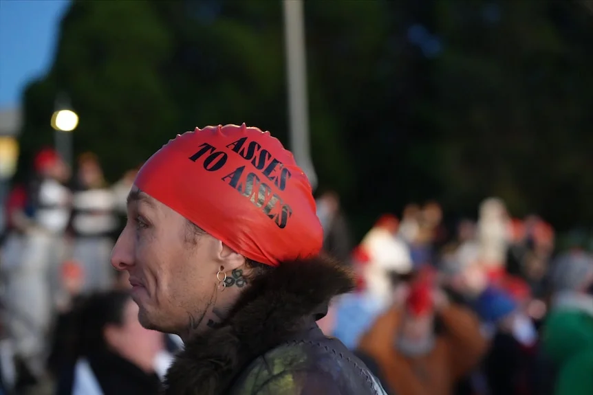 A person wearing a red swimming cap with the words "Asses to asses" printed on it.