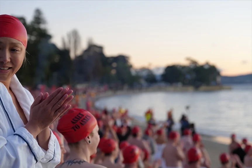 Crowd of swimmers prepare to enter the water for Dark Mofo's 2026 Nude Solstice Swim