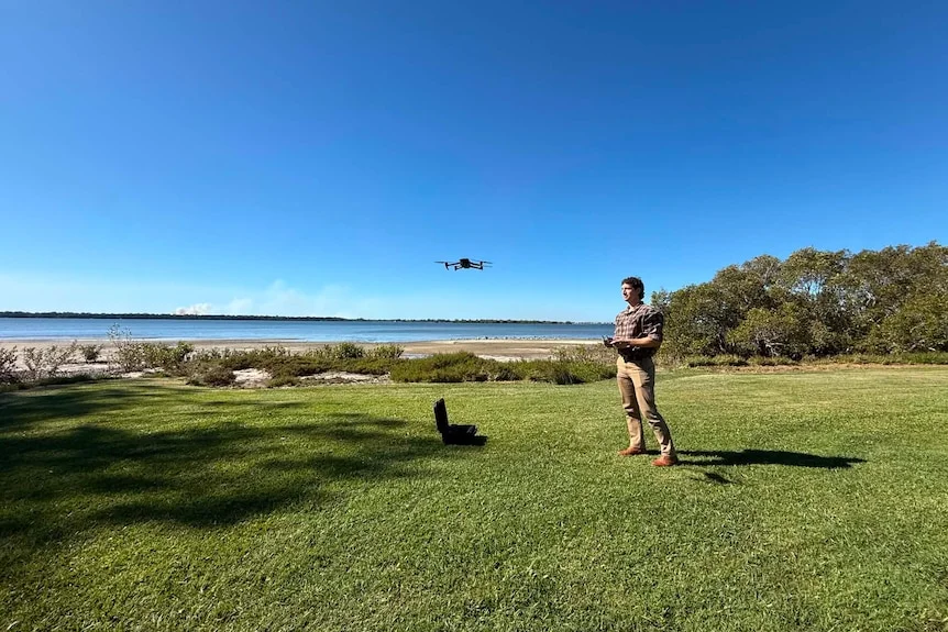 Man operating drone at shoreline