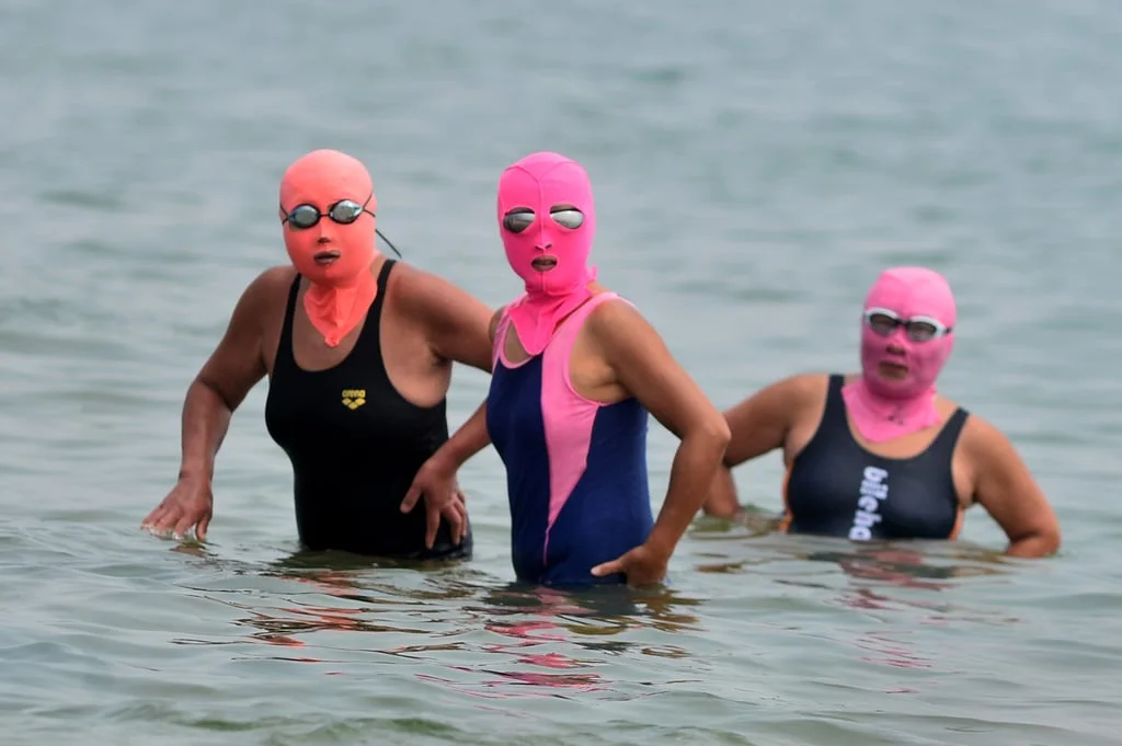 Three women wearing so-called facekinis to cool off while they bathe in the sea in China. Photo: Getty Images Three women wearing so-called facekinis to cool off while they bathe in the sea in China. Photo: Getty Images