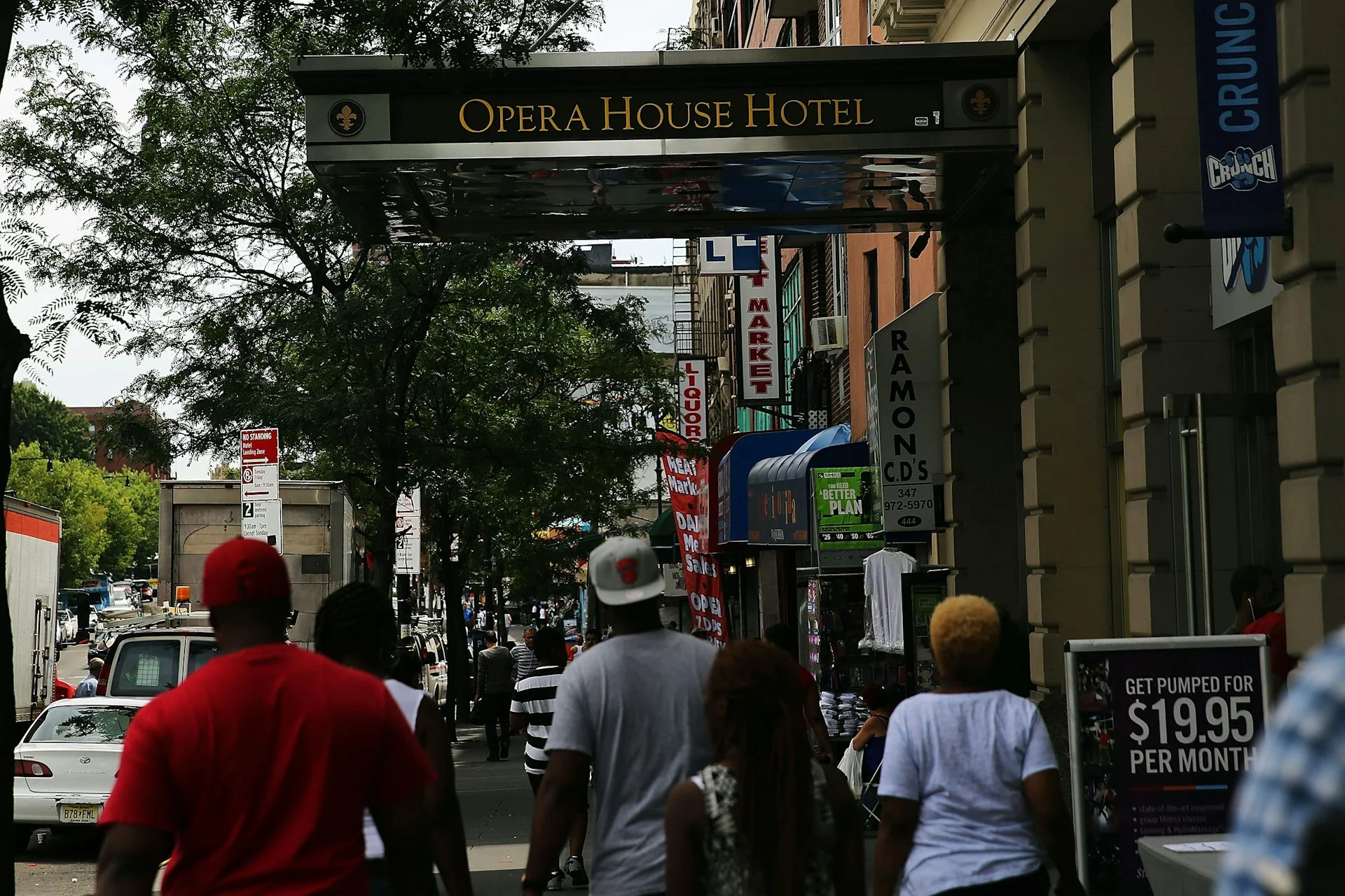 People walk down street near building that says Opera House Hotel