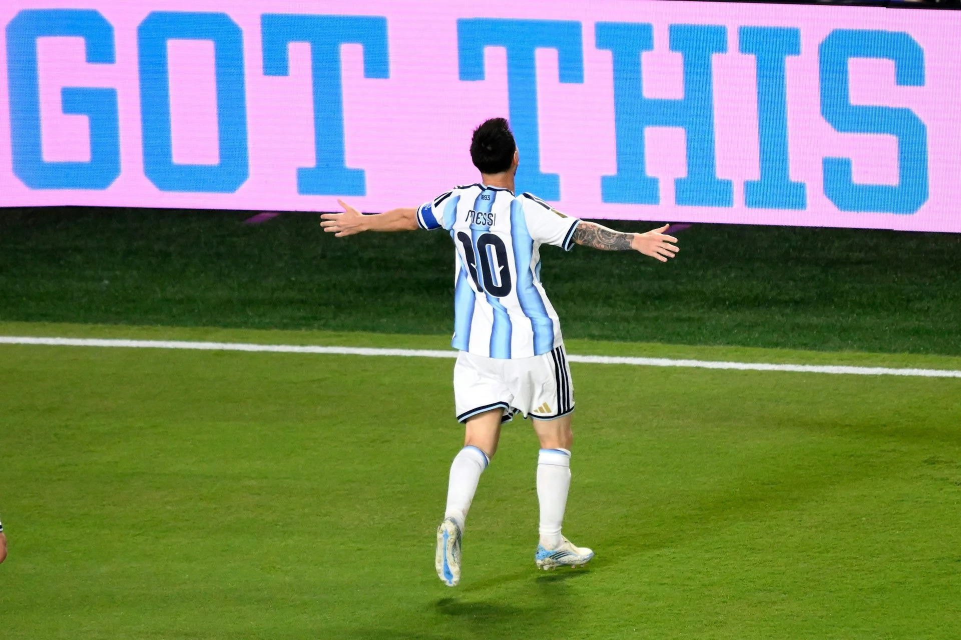 A man in a blue and white jersey has his arms outstretched.