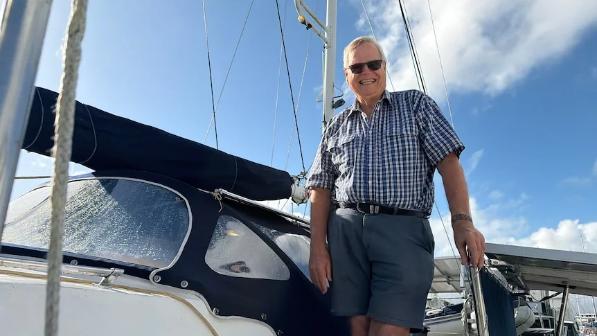 Older man wearing sunglasses standing next to boat