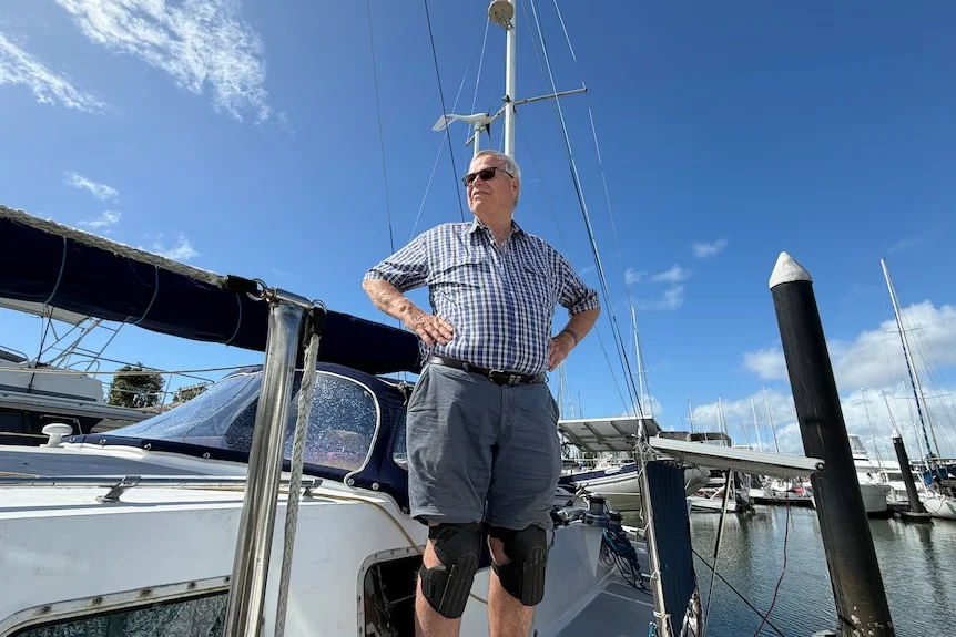 Older man with sunglasses looking out next to a boat at a marina