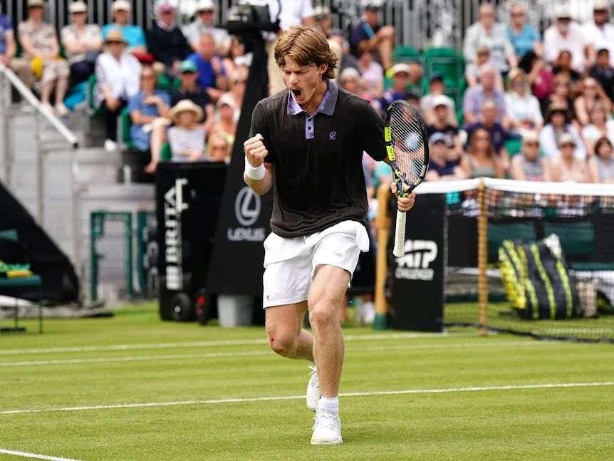 Dane, tennis player pumps his fist and screams in joy after winning a point.
